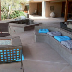 decorative concrete patio with benches and blue pillows